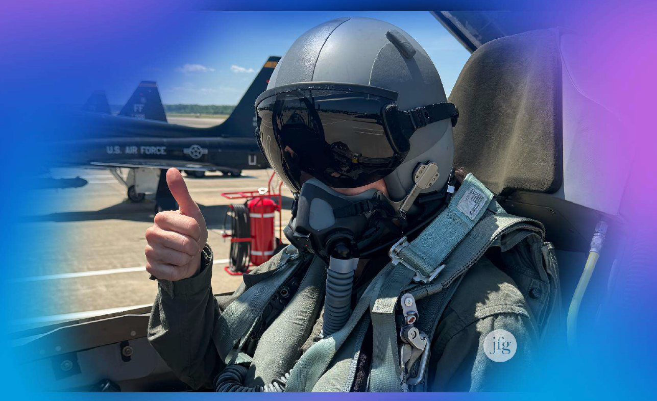 Juliet flies Funt in flight gear giving a thumbs up while seated in a jet cockpit, proprietary JFG image.