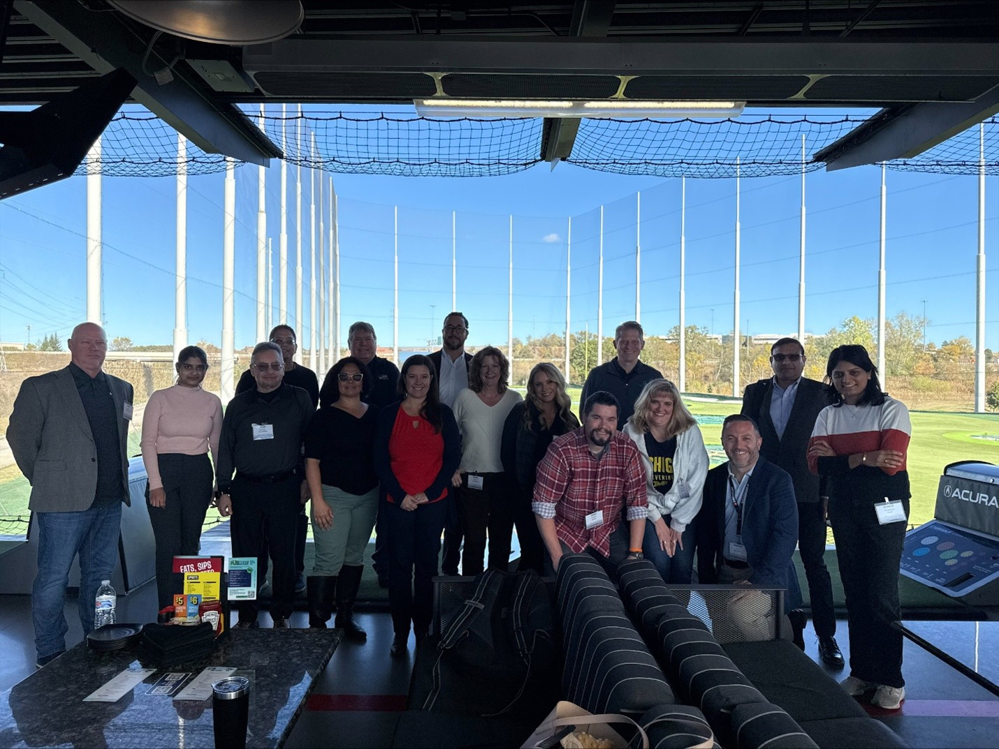 Group photo of Clarity user group attendees at a Topgolf venue during a networking event.